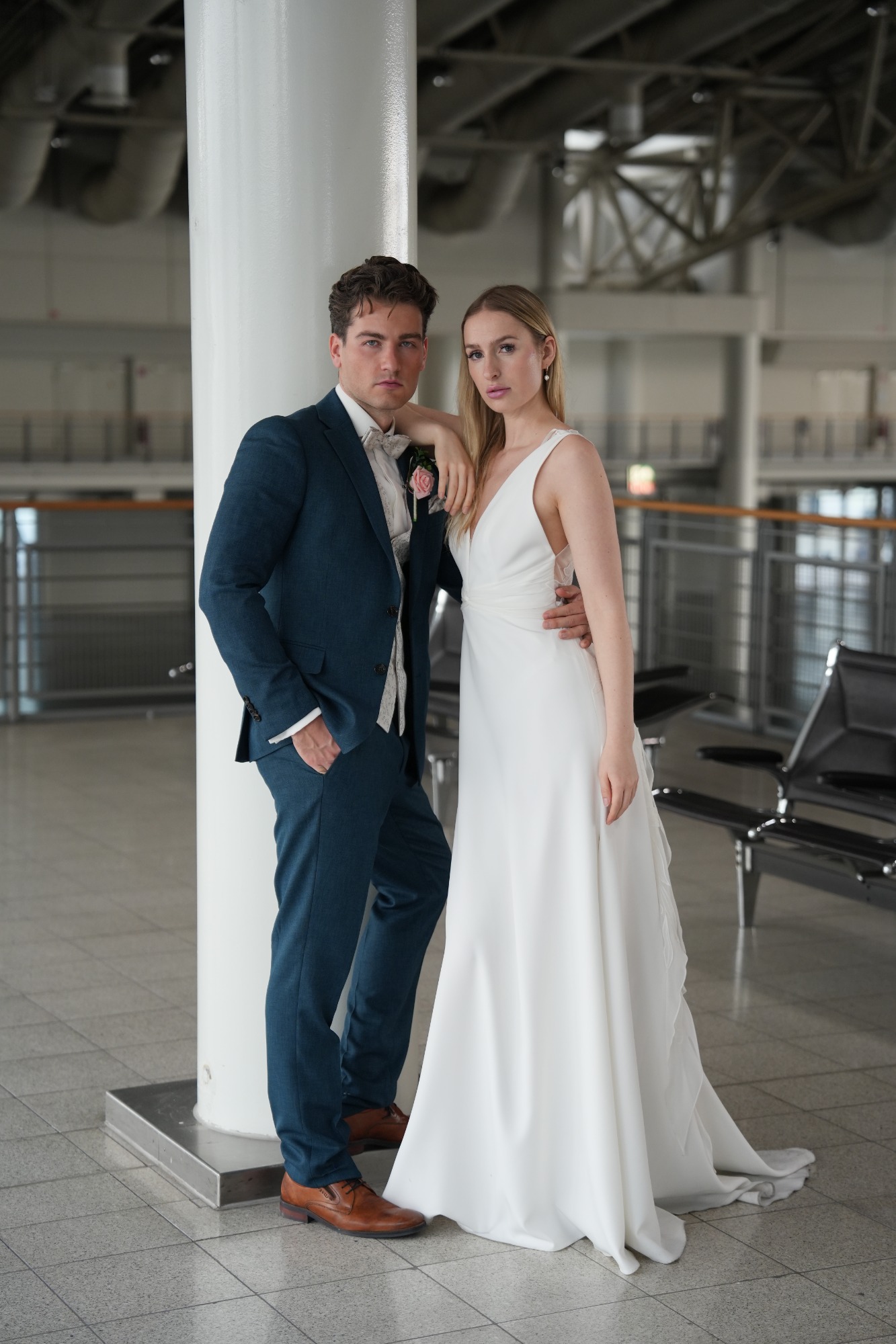 Braut und Bräutigam posieren elegant in einem modernen Innenraum.