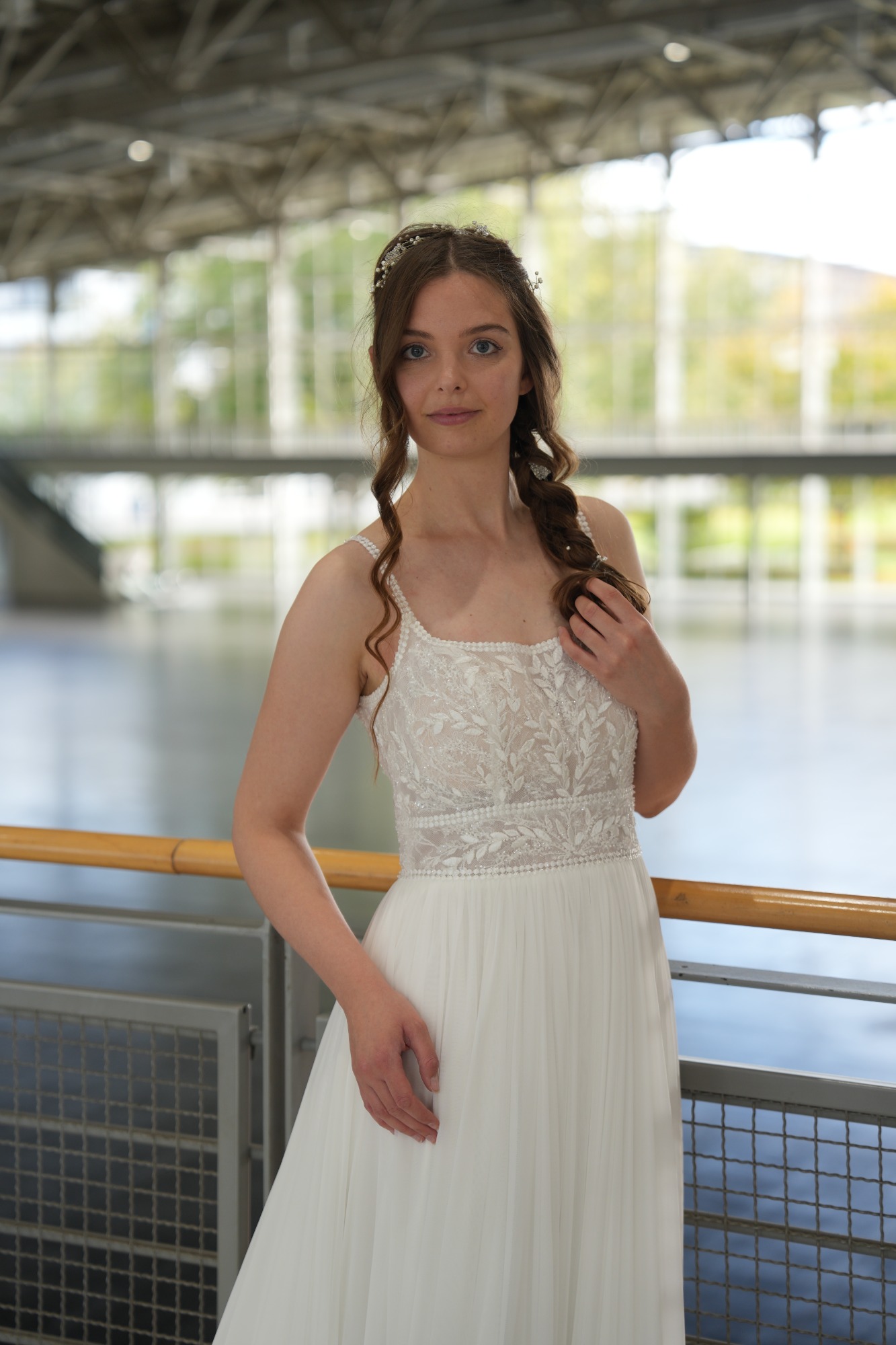 Frau in einem eleganten, weißen Kleid mit langen, lockigen Haaren in einem hellen Raum.