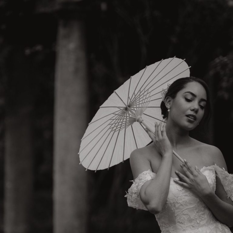satin-brautkleid-a-linie-klassisch Frau in einem eleganten Kleid hält einen weißen Sonnenschirm und posiert nachdenklich.