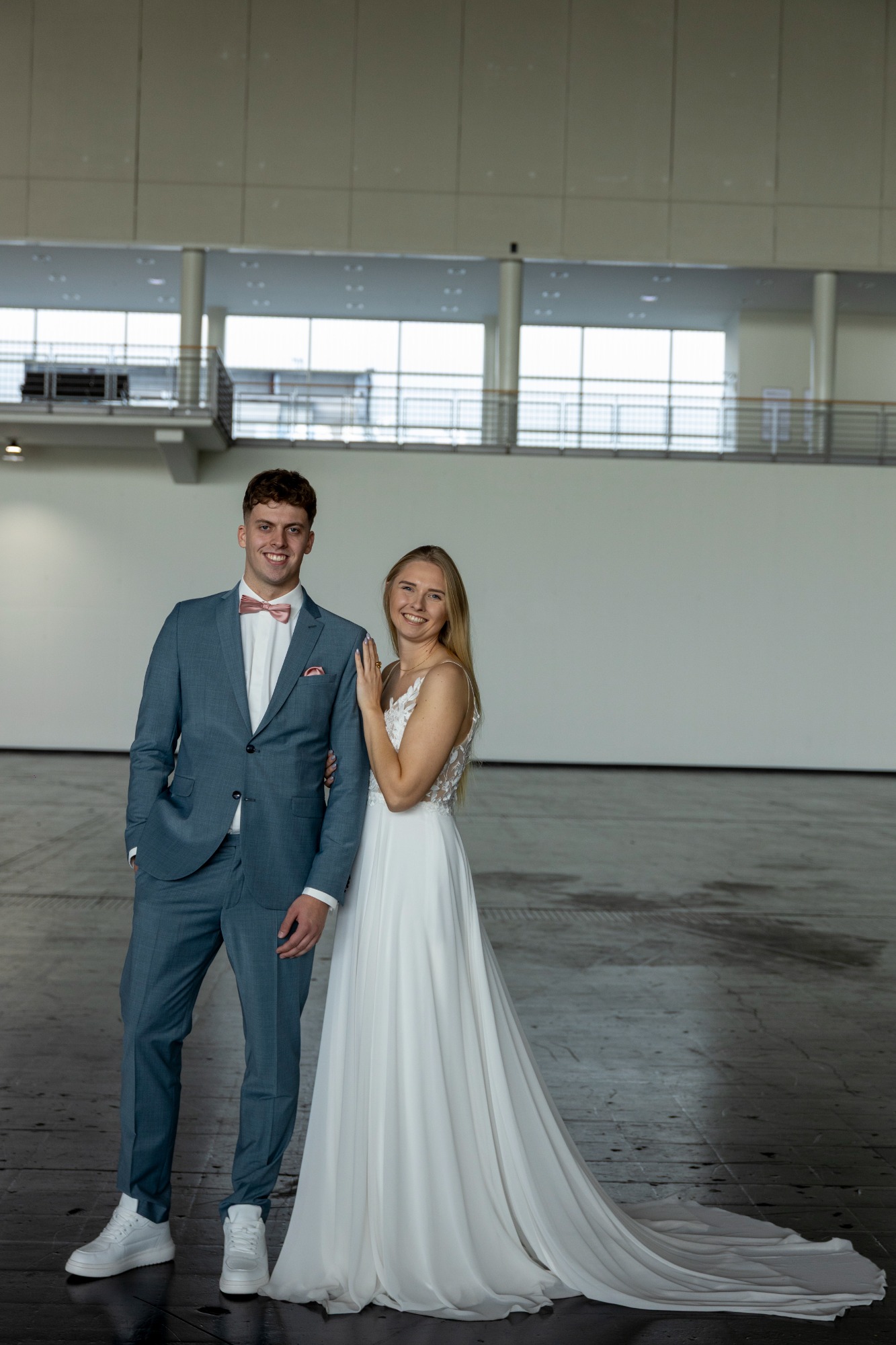 Hochzeitspaar posiert in eleganter Kleidung in einem modernen, hellen Raum.