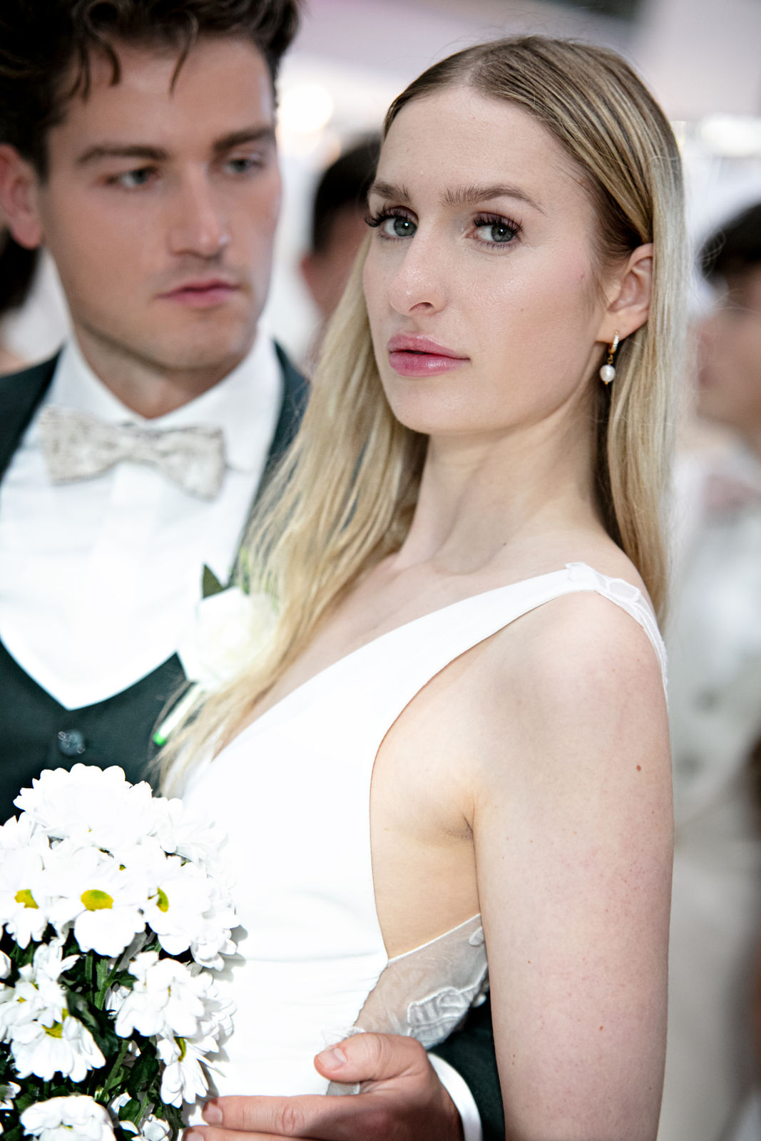 Brautpaar in eleganter Hochzeitskleidung, sie hält einen Blumenstrauß.