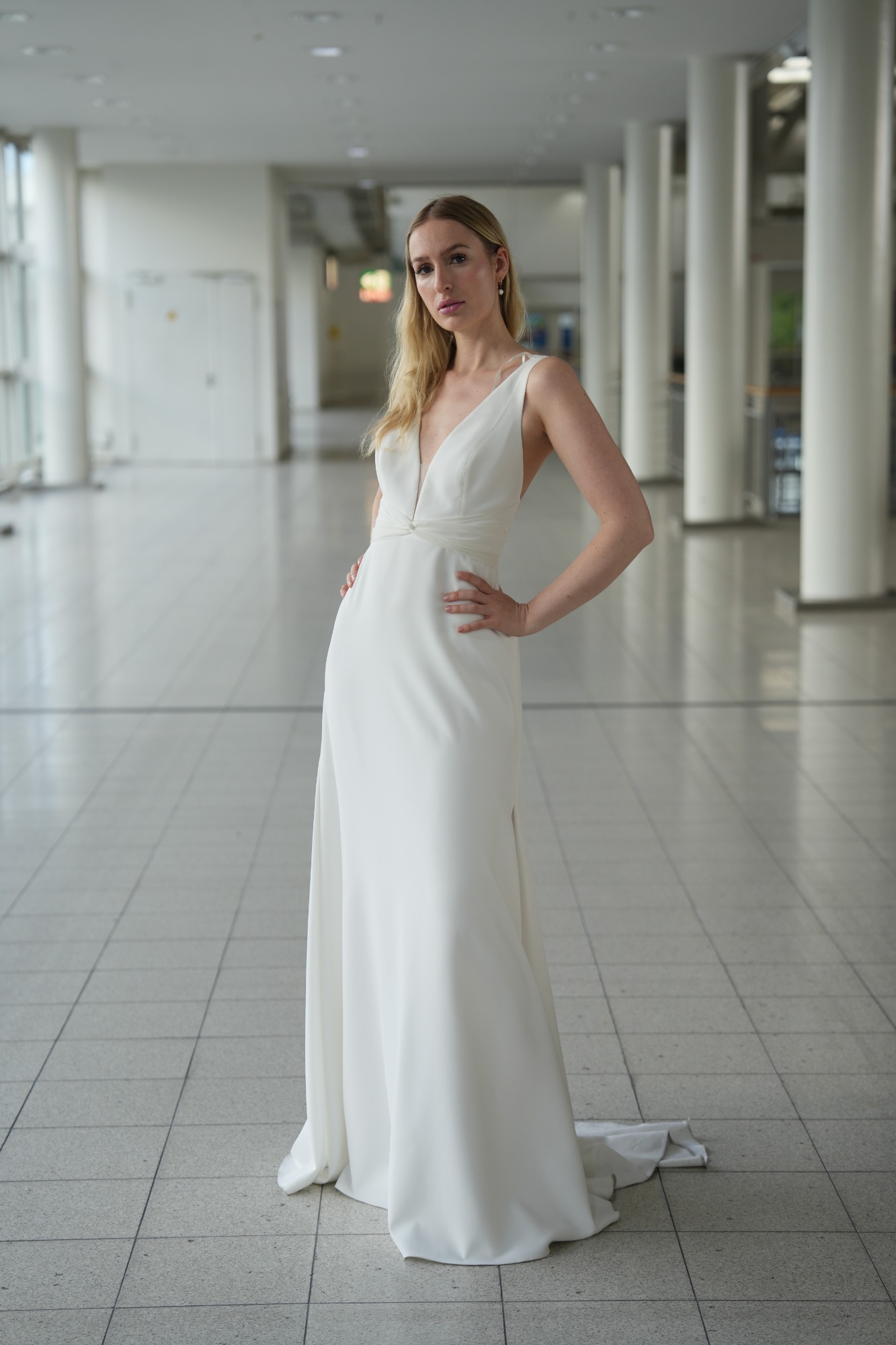 Eine Frau in einem eleganten, schlichten weißen Kleid steht in einem modernen Raum.