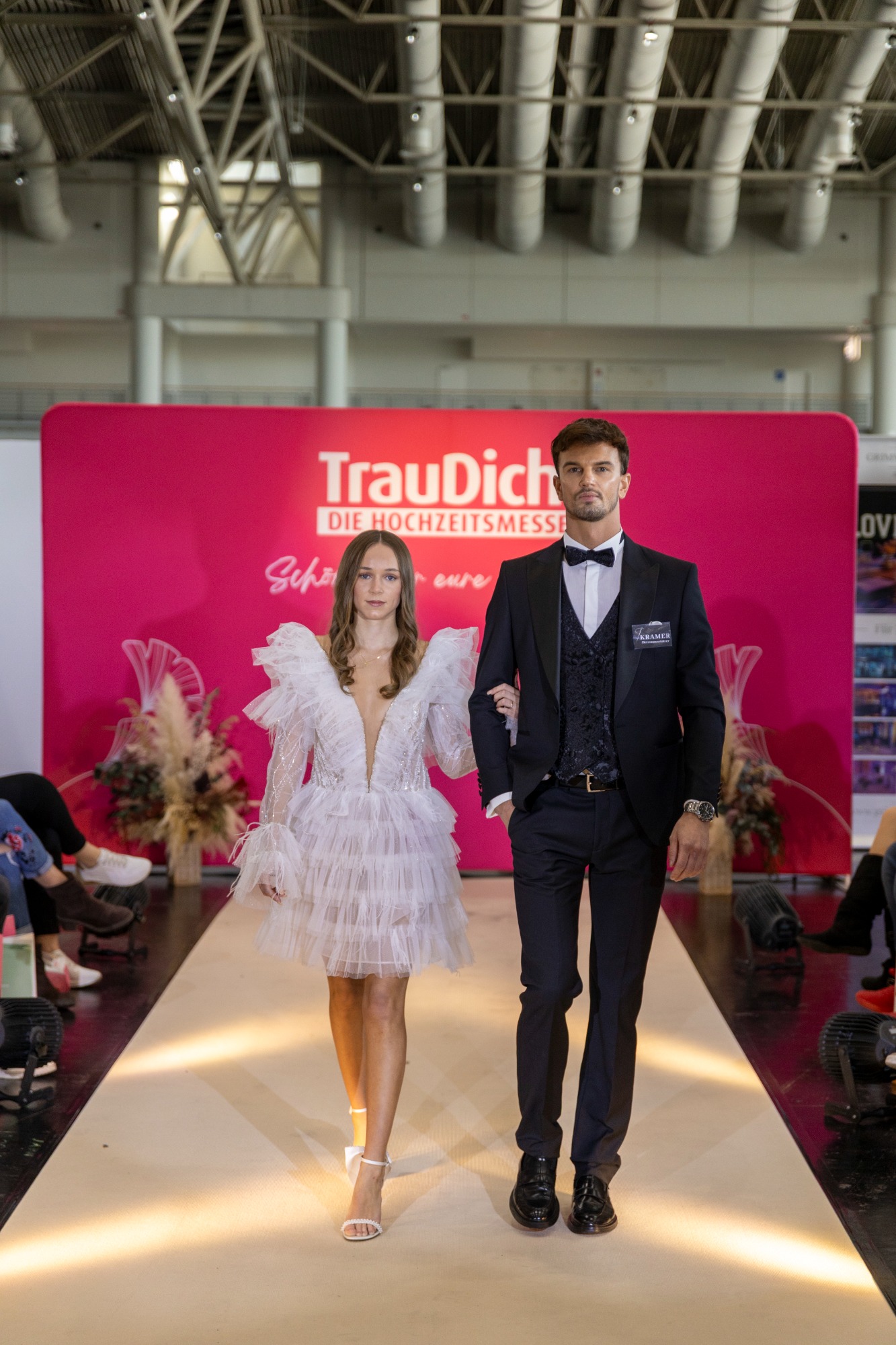 Brautpaar auf dem Laufsteg, elegant gekleidet, im Mittelpunkt einer Hochzeitsmesse.