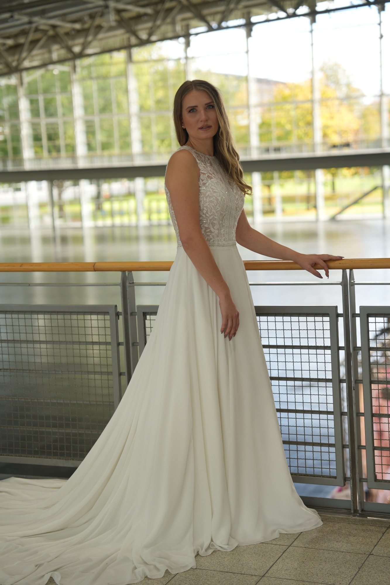 Eine Braut in einem eleganten, weißen Hochzeitskleid steht in einer modernen Umgebung.