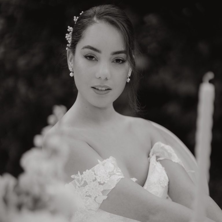 satin-brautkleid-a-linie-klassisch Porträt einer Frau in einem Brautkleid, umgeben von Blumen und Kerzen.